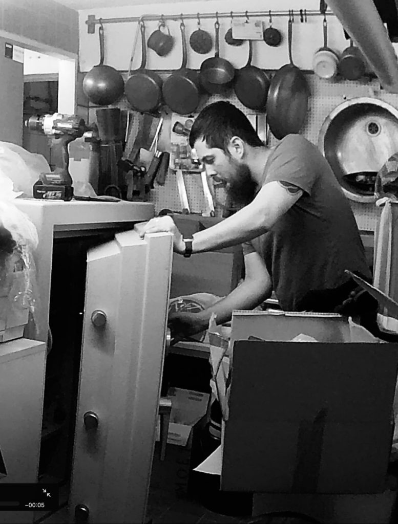 Techniker arbeitet an einem schwarzen Tresor mit geöffneter Tür – Tresoröffnung Bremen